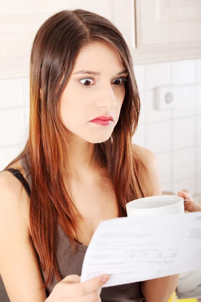 Mujer estresada en la cocina con factura —  Fotos de Stock