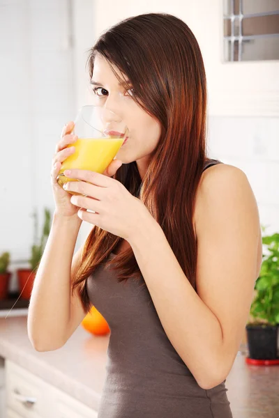 Porträt einer fröhlichen jungen lächelnden Frau, die frischen Orangensaft trinkt — Stockfoto