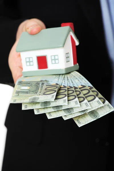 Businessman with money and house's model. — Stock Photo, Image