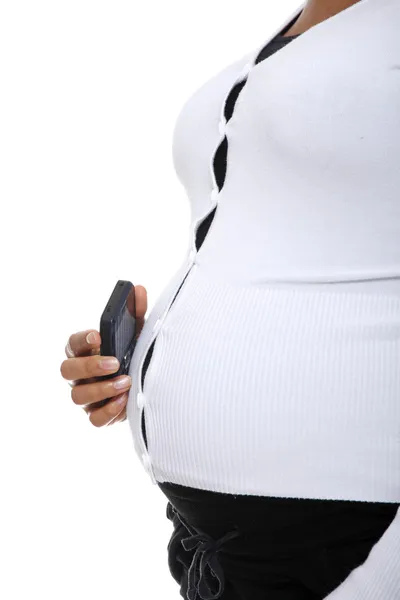 Mulher grávida segurando um celular contra a barriga . — Fotografia de Stock