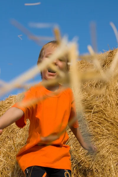 Boy stands on a large haystack — Stock Photo, Image