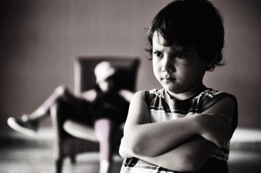 Old style photography: angry boy standing in front of relaxed girl in chair clipart