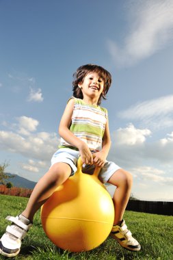 Little happy boy playing with big ball and jumping with slight motion up, s clipart