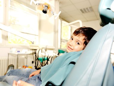 At dentist's modern working place, cute kid sitting on chair and smili clipart