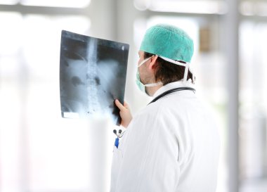 Medical doctor analysing x-ray image handheld, standing at office desk clipart