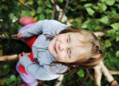 Beauty blond baby on tree leaves ground with closed eyes