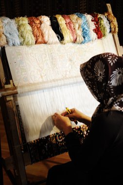 Woman working at the loom. Oriental Muslim national crafts. Focus on the fa