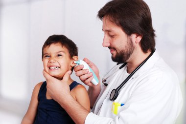 Male doctor examining a child patient in a hospital clipart