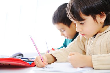 Two cute school boys working on their homework together clipart