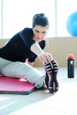 Fitness sporty girl with a ball at gym and bottle of water excercising clipart