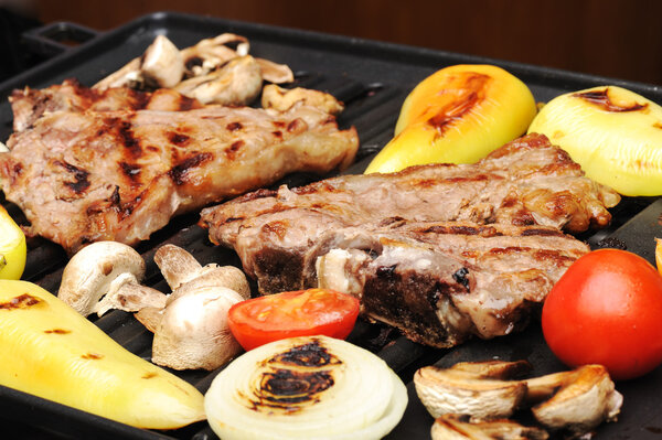 Barbecue, prepared beef meat and different vegetables and mushrooms on gril