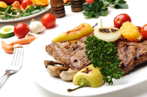 Gegrilltes Steakfleisch auf einem weißen Teller auf weißem Hintergrund — Stockfoto