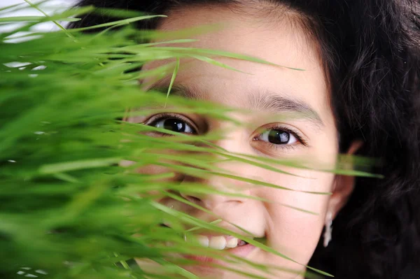 Menina e grama, rosto feliz por trás da cor verde — Fotografia de Stock