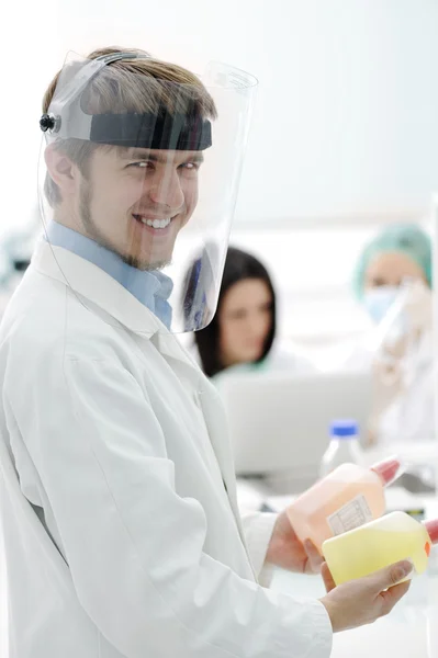 Jovem médico com máscara de vidro trabalhando com sua equipe em laboratório — Fotografia de Stock