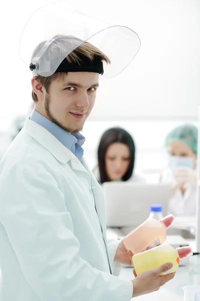 Young medical worker with glass mask working with his team in lab — Stock Photo, Image