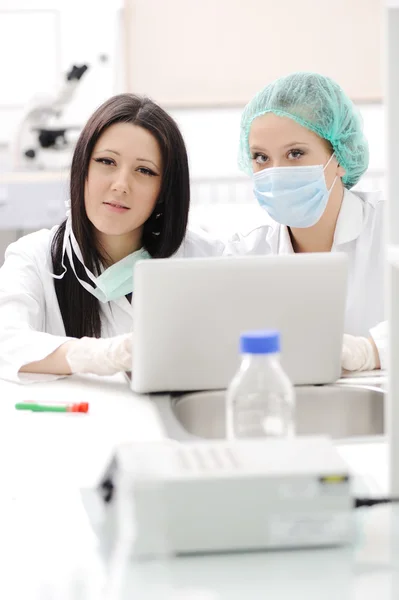 Две женщины-учёные работают в лаборатории с ноутбуком — стоковое фото