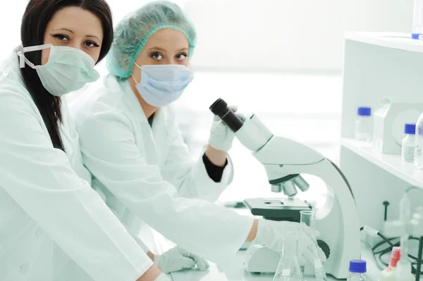 Дві жінки-вчені працюють в лабораторії з мікроскопом — стокове фото