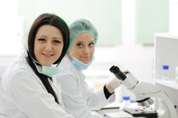 Dos científicas trabajando en el laboratorio con microscopio — Foto de Stock