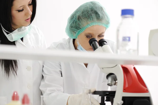 Zwei Wissenschaftlerinnen arbeiten im Labor unter dem Mikroskop — Stockfoto