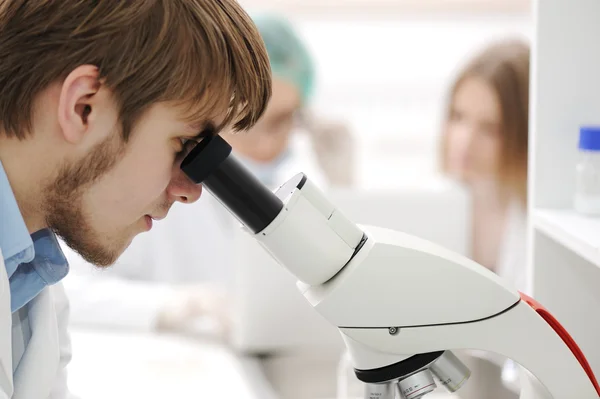 Grupo de alunos que trabalham no laboratório com microscópio — Fotografia de Stock