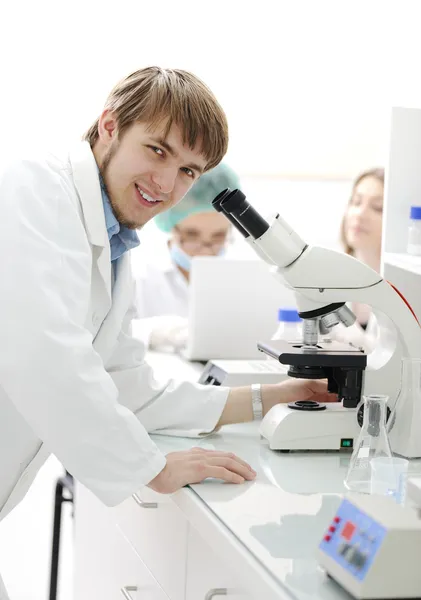 Science team working with microscopes in a laboratory, young researcher smi — Stock Photo, Image