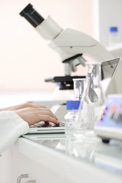 Lavorare in laboratorio con microscopio e scrivere risultati su laptop, primo piano — Foto Stock