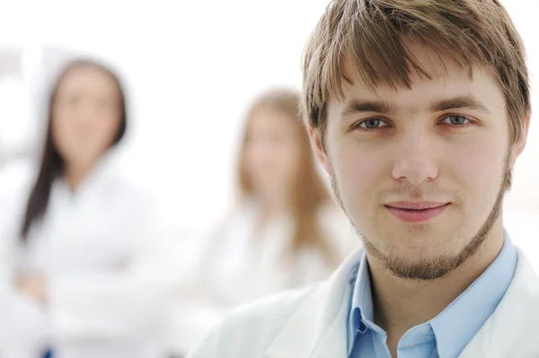 自信的年轻医生在医院实验室、 特写的脸和他的团队在后面喜 — 图库照片