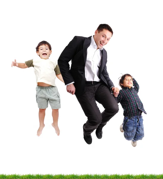 Pai e filhos pulando sobre grama verde, isolado — Fotografia de Stock