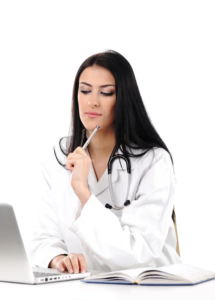 Young woman doctor in white coat at computer thinking — Stock Photo, Image