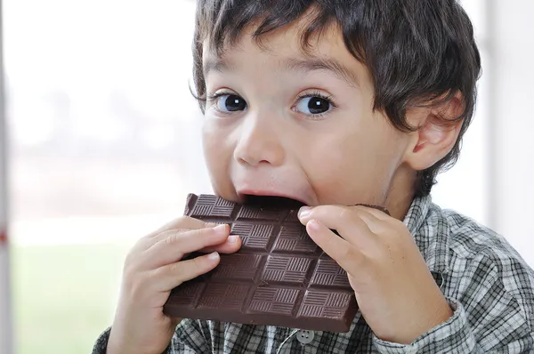 Weinig schattige jongen eten van chocolade — Stockfoto