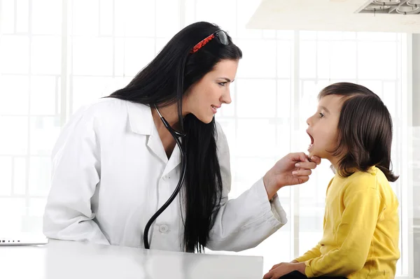 Женщина-врач осматривает ребенка с депрессором языка — стоковое фото