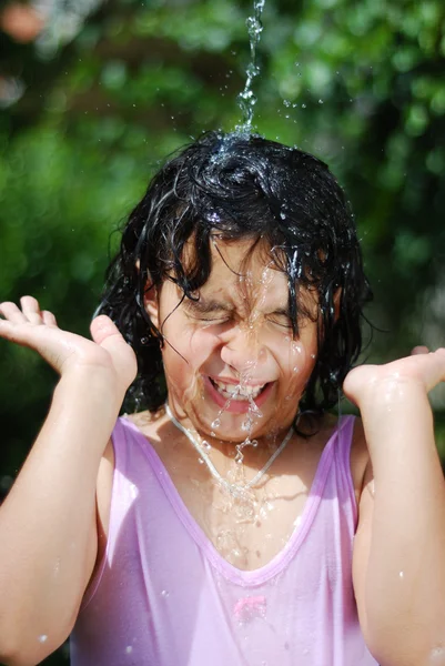 Malá holčička, stříkající vodou v horké léto — Stock fotografie