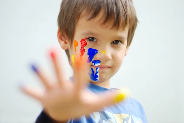 Мальчик с цветными пальцами и лицом — стоковое фото