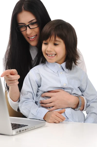 Feliz joven hermosa madre y lindo hijo pequeño en el ordenador portátil en la mesa —  Fotos de Stock