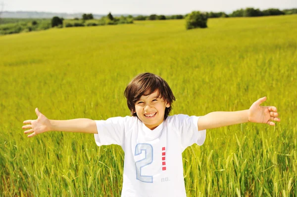 Niño feliz en la naturaleza, niño sonriente positivo en verde hermoso prado con —  Fotos de Stock