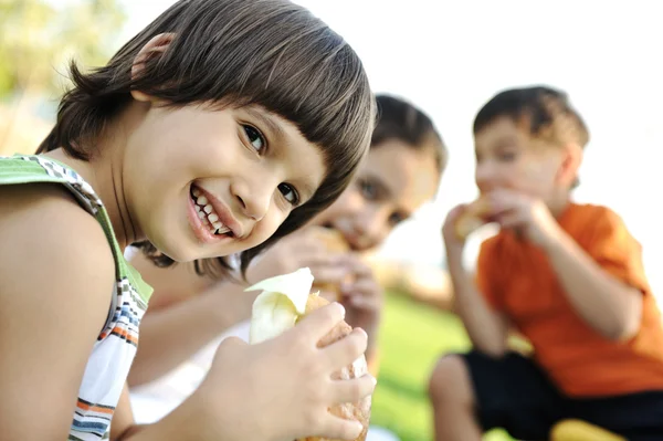Pequeno grupo de crianças na natureza comendo lanches juntos, sanduíches, pão — Fotografia de Stock