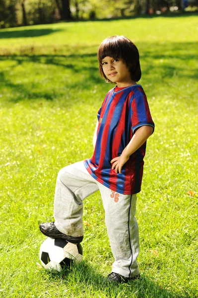 Ładny mały chłopiec z piłką w pięknym parku w przyrodzie — Zdjęcie stockowe