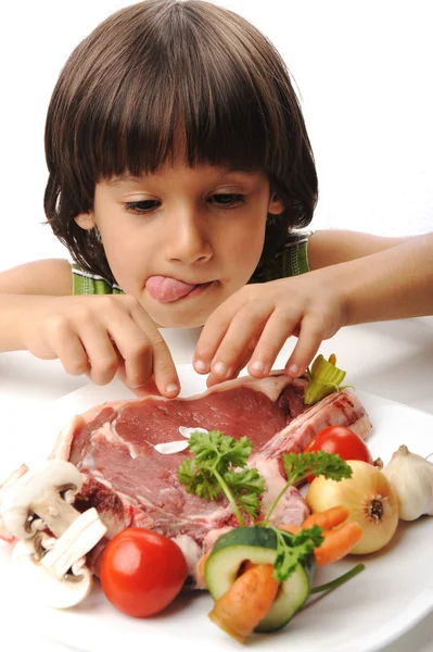 Carino ragazzo positivo e carne cruda e verdure in lettura del piatto per cucinare — Foto Stock