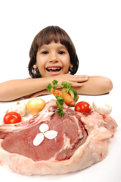 Lindo chico positivo y carne cruda y verduras en plato de lectura para cocinar —  Fotos de Stock