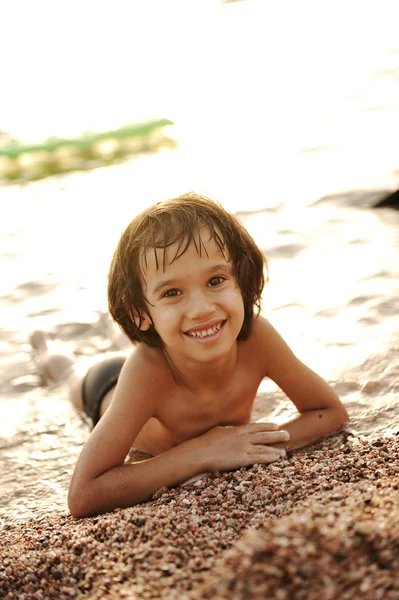 Liten pojke om på stranden före solnedgången — Stockfoto