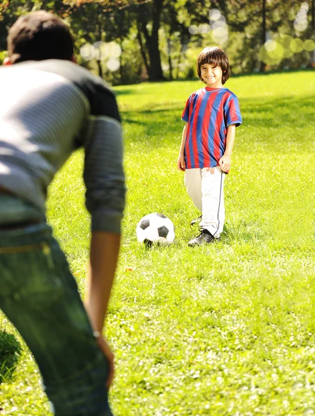 Schattige kleine jongen met zijn vader spelen met een bal in een prachtig park in nb — Stockfoto