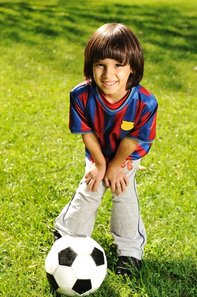 Söt liten pojke leker med en boll i vacker park i naturen — Stockfoto