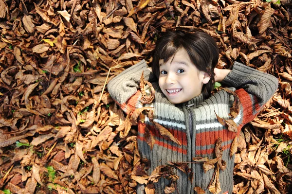 Retrato de cerca de un hermoso niño de otoño tendido en el suelo — Foto de Stock