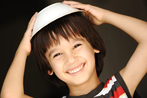 Милый ребенок с тарелкой на голове улыбается — стоковое фото