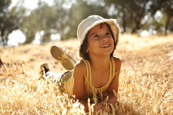 Slarvig pojke på gult gräs äng i höst — Stockfoto