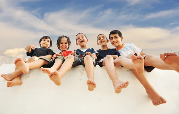 Cinco amigos felizes sentados na parede ao ar livre — Fotografia de Stock