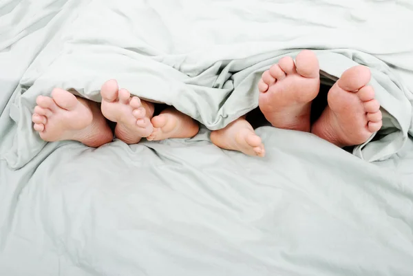 Gelukkig familie in bed onder blad — Stockfoto
