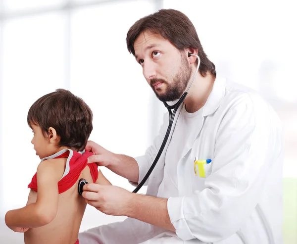 Young doctor examining little boy in hospital — Stock Photo, Image