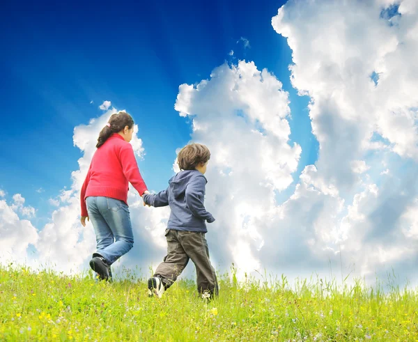 Crianças felizes correndo em madow com céu bonito contra eles — Fotografia de Stock