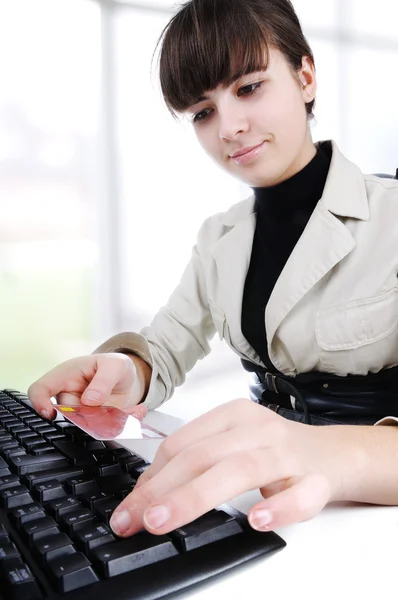 As mãos de mulher e computador portátil com um cartão de crédito na mão - escritório moderno — Fotografia de Stock
